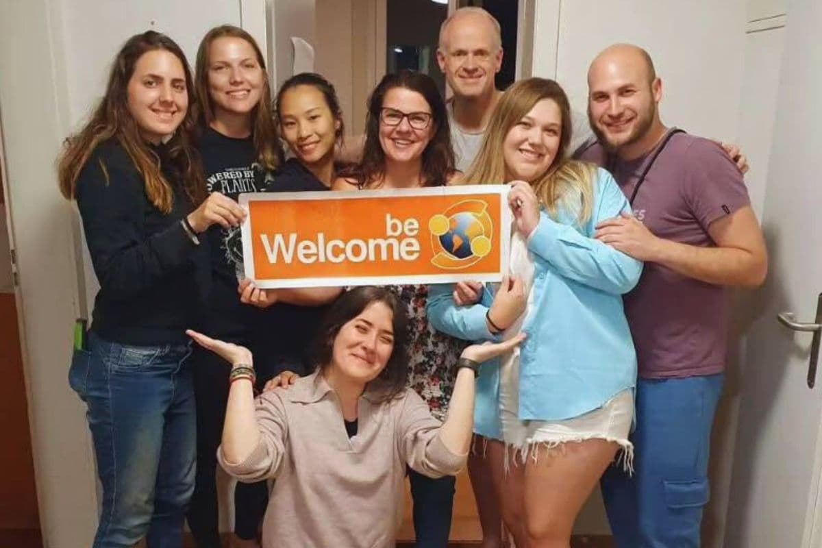 Happy volunteers holding welcome sign